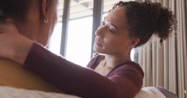 Romantik çift ırklı lezbiyen çift koltukta birlikte dinleniyor, sarılıyorlar ve konuşuyorlar, ağır çekimde. Yaşam tarzı, ilişki, birliktelik, rahatlama, aşk ve ev hayatı, değişmemiş..