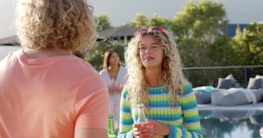 Güneşli havuz partisinde çeşitli arkadaşlarla içki içen mutlu beyaz çift, yavaş çekim. Yaz, yaşam tarzı, arkadaşlık, kutlama ve parti, değişmeden.