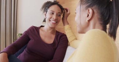 Çift ırklı mutlu çift koltukta birlikte dinleniyor, gülümsüyor ve yavaş çekimde konuşuyor. Yaşam tarzı, ilişki, birliktelik, rahatlama, aşk ve ev hayatı, değişmemiş..