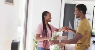 Mutlu Afro-Amerikan çifti oturma odasında el ele tutuşup dans ediyor, ağır çekimde. Yaşam tarzı, ilişki, eğlence, romantizm, birliktelik, aşk ve aile hayatı, değişmemiş.