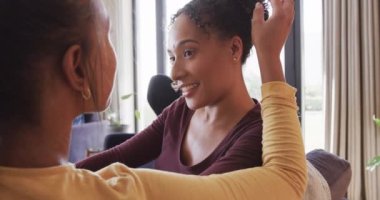 Romantik çift ırklı lezbiyen çift koltukta birlikte dinleniyor, gülümsüyor ve yavaş çekimde konuşuyorlar. Yaşam tarzı, ilişki, birliktelik, rahatlama, aşk ve ev hayatı, değişmemiş..