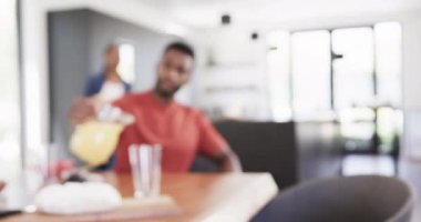 Mutlu Afro-Amerikan çifti meyve suyu dolduruyor ve kahvaltıyı güneşli mutfakta sunuyor, ağır çekimde. Yaşam tarzı, birliktelik, yemek, yemek, yemek pişirme ve ev hayatı, değişmemiş..