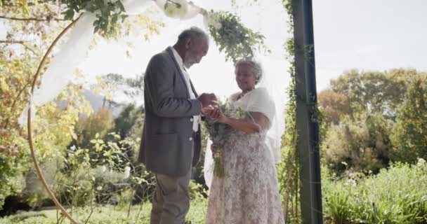 Щаслива Старша Пара Обмінюється Кільцями Під Час Весільної Церемонії Саду — стокове відео