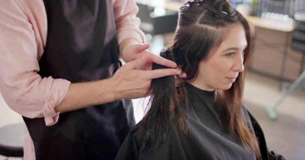 白人男性の美容師は女性の顧客の髪を保持し サロンで彼女に助言します スローモーション 地元のビジネス ヘアケア ヘアスタイリング 変更なし — ストック動画
