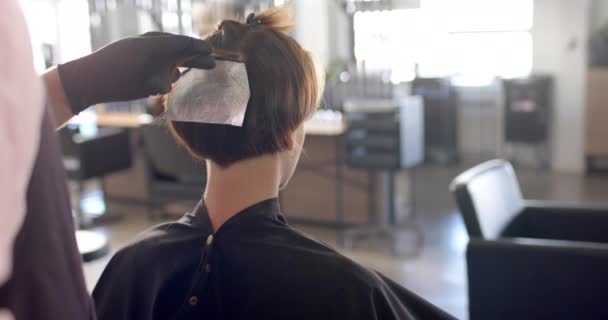 サロンで箔でクライアントの髪を強調白人男性の美容師の手 スローモーションで 地元のビジネス 美容業界 ヘアカラーとヘアスタイリング — ストック動画