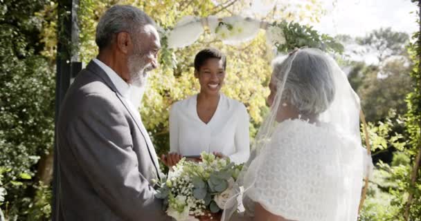 Afroamerikansk Kvinna Som Förrättar Bröllopsceremoni För Äldre Biracial Par Trädgården — Stockvideo
