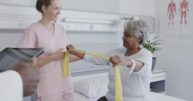 Çeşitli erkek doktorlar kadın fizyoterapist ve mutlu yaşlı kadın hasta ile konuşuyor, ağır çekimde. Sağlık hizmetleri, hastane, kontrol, takım çalışması, fizyoterapi ve sağlık hizmetleri, değiştirilmemiş.