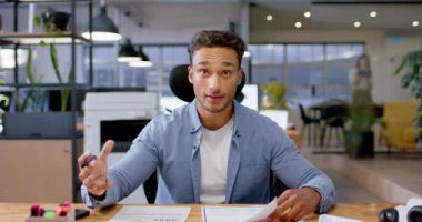 Çift ırklı iş adamı video görüşmesi sırasında konuşuyor, ofiste geç saatlere kadar çalışıyor, ağır çekimde. İş, iletişim, günlük ofis ve geç saatlere kadar çalışma, değiştirilmemiş.