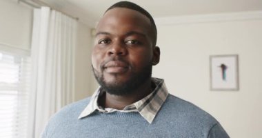 Mutlu Afro-Amerikan bir adamın portresi. Kameraya bakıyor ve evinde gülümsüyor. Ağır çekimde. Mutluluk, yaşam tarzı ve aile hayatı, değişmez..