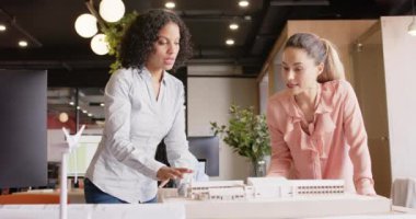 Çeşitli kadın mimarlar iş yerindeki mimari modelleri yavaş çekimde tartışıyorlar. Takım çalışması, ofis, mimari, yaratıcı iş ve tasarım, değiştirilmemiş.