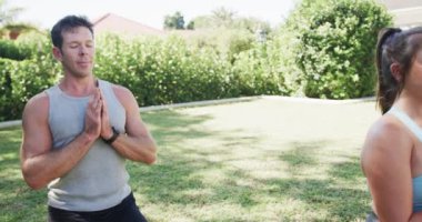 Güneşli bahçede yoga meditasyonu yapan mutlu beyaz çift, ağır çekimde. Aktif yaşam tarzı, sağlık ve sağlık, değiştirilmemiş.