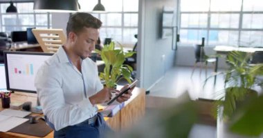 Ofiste tablet kullanan, gülümseyen ve ağır çekimde gülümseyen zeki, çift ırklı iş adamının portresi. İş, iletişim, ofis ve iş, değiştirilmemiş.