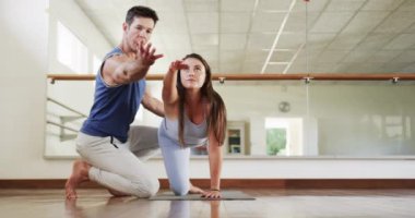 Kafkas erkek eğitmen ve kadın öğrenci jimnastik salonunda yoga yapıyor, ağır çekimde. Aktif yaşam tarzı, yoga duruşu, eğitim, sağlık ve sağlık, değişmemiş.