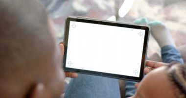 Mutlu Afro-Amerikan baba ve oğlu evde tablet kullanıyor. Ekranda kopya alanı var, ağır çekimde. Aile, iletişim, birliktelik ve aile hayatı değişmedi..