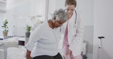 Kıdemli bayan hastaya yataktan kalkması için yardım eden mutlu kadın doktor, yavaş çekim. Sağlık hizmetleri, sağlık kontrolü, kıdemli sağlık, hastane ve sağlık hizmetleri, değiştirilmemiş.