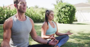 Güneşli bahçede yoga meditasyonu yapan mutlu beyaz çift, ağır çekimde. Aktif yaşam tarzı, nilüfer pozisyonu, sağlık ve sağlık, değişmemiş.