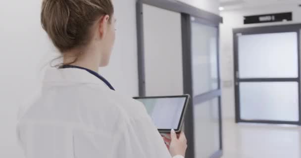 Vrolijke Blanke Vrouwelijke Arts Loopt Ziekenhuisgang Met Behulp Van Tablet — Stockvideo