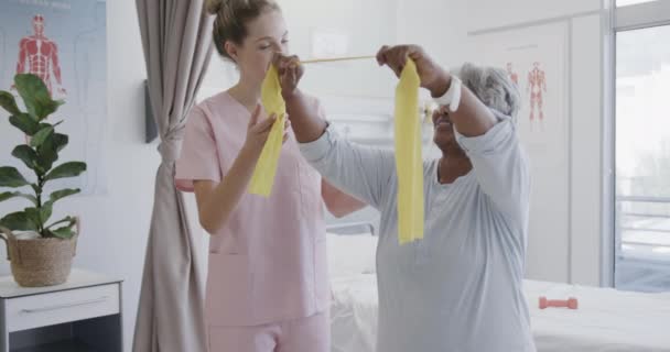 Fisioterapeuta Femenina Diversa Feliz Paciente Mayor Usando Bandas Ejercicio Cámara — Vídeos de Stock