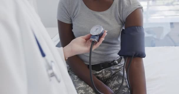 病院で血圧を測定する幸せな多様な女性兵士の患者と医師 スローモーションで 医療サービス チェックアップ 軍事サービス 病院や医療 変更なし — ストック動画