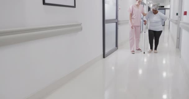 Diverse Vrouwelijke Arts Helpt Oudere Vrouwelijke Patiënt Lopen Met Stok — Stockvideo
