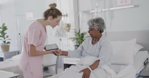 快乐多样的女医生用平板电脑和年长的女病人在床上交谈 动作缓慢 医疗服务 老年人健康 医院和医疗保健 未经改动 — 图库视频影像