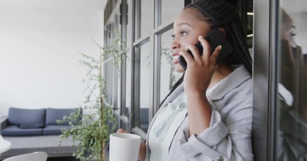 Серйозна Афроамериканська Випадкова Бізнесменка Яка Розмовляє Телефону Тримаючи Каву Офісі — стокове відео