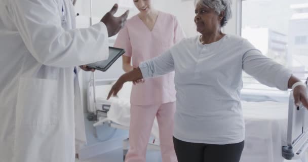 不同的男医生用平板和快乐的女性体质治疗老年女性患者 动作缓慢 医疗服务 协同工作 理疗和保健 未经改动 — 图库视频影像