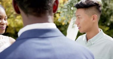 Mutlu Afrikalı Amerikalı çiftin evliliğini ağır çekimde, güneşli bahçede yürüten melez bir adam. Yaz, düğün, romantizm, aşk, gelenek ve kutlama.