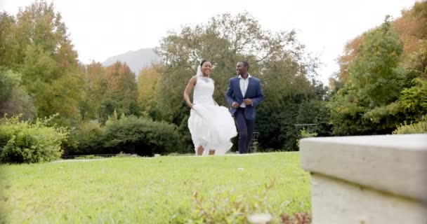 庭での結婚式で幸せなアフリカ系アメリカ人の花嫁と新郎のジャンプや抱擁 スローモーション ロマンス 伝統とお祝い 変更なし — ストック動画