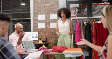 Moda stüdyosunda kadın ve erkek tasarımcılar yavaş çekimde kıyafetleri tartışırken mutlu olun. Moda, gündelik ofis, iş, takım çalışması, tasarım ve yaratıcı çalışma.