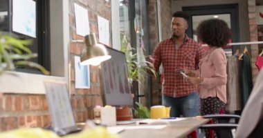 Moda stüdyosundaki cam duvara yavaş çekimde beyin fırtınası yapan mutlu erkek ve kadın tasarımcılar. Moda, gündelik ofis, iş, takım çalışması, tasarım ve yaratıcı çalışma.