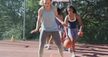 Mutlu çeşitli bayan basketbol takımları yavaş çekimde güneşli sahada antrenman yapıyor. Spor, fitness, sağlık ve açık hava aktiviteleri, değiştirilmemiş.