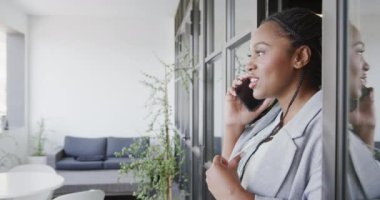 Mutlu Afro-Amerikan iş kadını ofis salonunda akıllı telefonuyla konuşuyor, ağır çekimde. İş, iletişim, ofis ve iş, değiştirilmemiş.