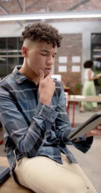 Çift ırklı iş adamının ofiste ağır çekimde tablet kullandığı dikey bir video. Küresel iş, teknoloji ve çalışma.
