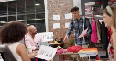 Moda stüdyosundaki kadın ve erkek tasarımcılar yavaş çekimde mutlu bir şekilde toplanıyor. Moda, gündelik ofis, iş, takım çalışması, tasarım ve yaratıcı çalışma.