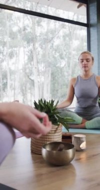 Yoga dersindeki paspaslar üzerinde birlikte meditasyon yapan farklı kadınların dikey videosu, yavaş çekim. Refah, zindelik, egzersiz ve sağlıklı yaşam tarzı, değişmemiş..