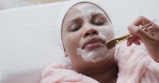 Kosmetikerin Trägt Schönheitsmaske Auf Das Gesicht Einer Afrikanisch Amerikanischen Size — Stockvideo