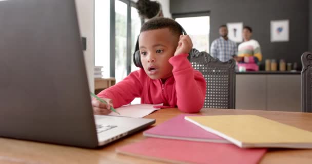 アフリカ系アメリカ人の少年は オンラインレッスン スローモーションで手を上げるヘッドフォンやラップトップを使用しています 子供時代 コミュニケーション オンライン学習と国内生活 変更なし — ストック動画