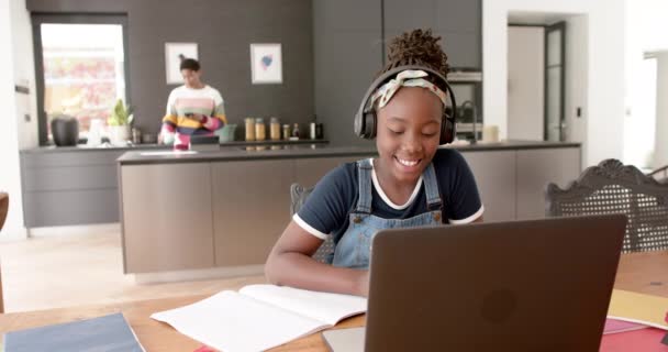ハッピーアフリカ系アメリカ人の女の子は スローモーションでヘッドフォンとラップトップを使用してオンラインクラスです 幼少期 コミュニケーション オンライン学習 家庭生活 — ストック動画