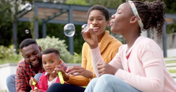 Felices Padres Afroamericanos Hijo Hija Soplando Burbujas Soleado Jardín Familia — Vídeo de stock