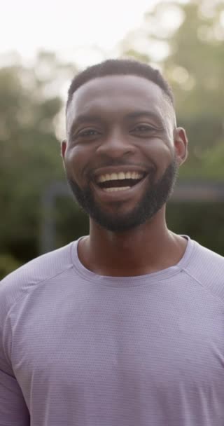 庭で笑っている幸せなアフリカ系アメリカ人男性の垂直ビデオポートレート スローモーションで 幸福とリラックスと幸福 — ストック動画