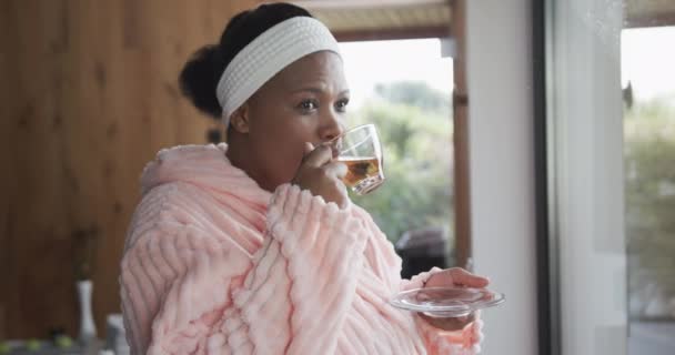 アフリカ系アメリカ人のプラスサイズの女性のバスローブを着て スパでお茶を飲んで 変更されていない スローモーション 美しさ リラクゼーションと身体の包容力 — ストック動画