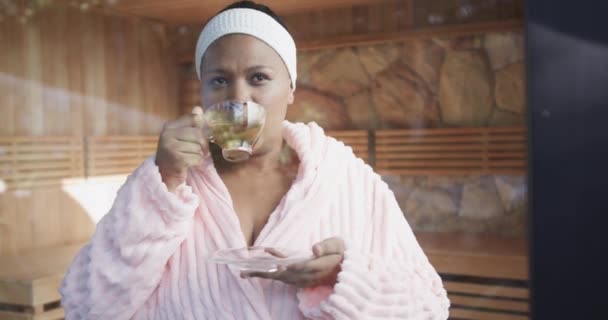 African American Size Woman Wearing Bathrobe Drinking Tea Spa Unaltered — Stock Video