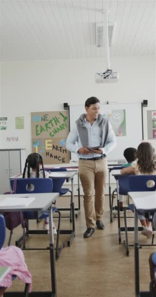 遅い動きで教室で書く幸せな多様な男性教師と学童の垂直ビデオ 教育変更なし — ストック動画
