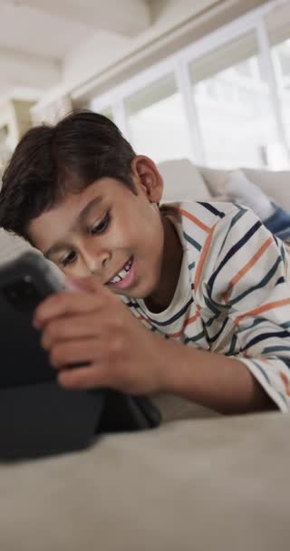 Vídeo Vertical Niño Birracial Acostado Sofá Usando Una Tableta Casa — Vídeos de Stock