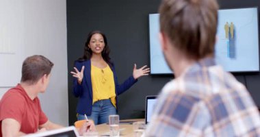 Mutlu Afro-Amerikan günlük iş adamı çeşitli meslektaşlarına toplantıda sunar, ağır çekimde. İş, iletişim, sunum, toplantı, günlük ofis ve iş, değiştirilmemiş.