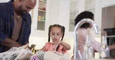 Mutlu çift ırklı babalar, anne ve kız mutfaktan alışveriş yapıyor, yavaş çekim. Alışveriş, yemek, aile, sağlıklı yaşam, yaşam tarzı ve ev hayatı, değişmemiş..