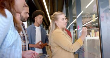 Cam duvara notlar yazarak beyin fırtınası yapan çeşitli yaratıcı meslektaşların kutlu olsun. Günlük ofis, beyin fırtınası, iş, takım çalışması ve yaratıcı çalışma, değiştirilmemiş..