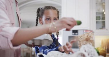 Çift ırklı anne ve kız mutfakta alışveriş yapıyor, ağır çekimde. Alışveriş, yemek, aile, sağlıklı yaşam, yaşam tarzı ve ev hayatı, değişmemiş..