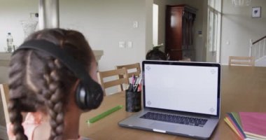 Çift ırklı kız, ekranda kopya alanı olan dizüstü bilgisayarı kullanarak internette öğreniyor. Ağır çekimde. Eğitim, iletişim, çevrimiçi öğrenme, çocukluk ve ev hayatı, değiştirilmemiş.